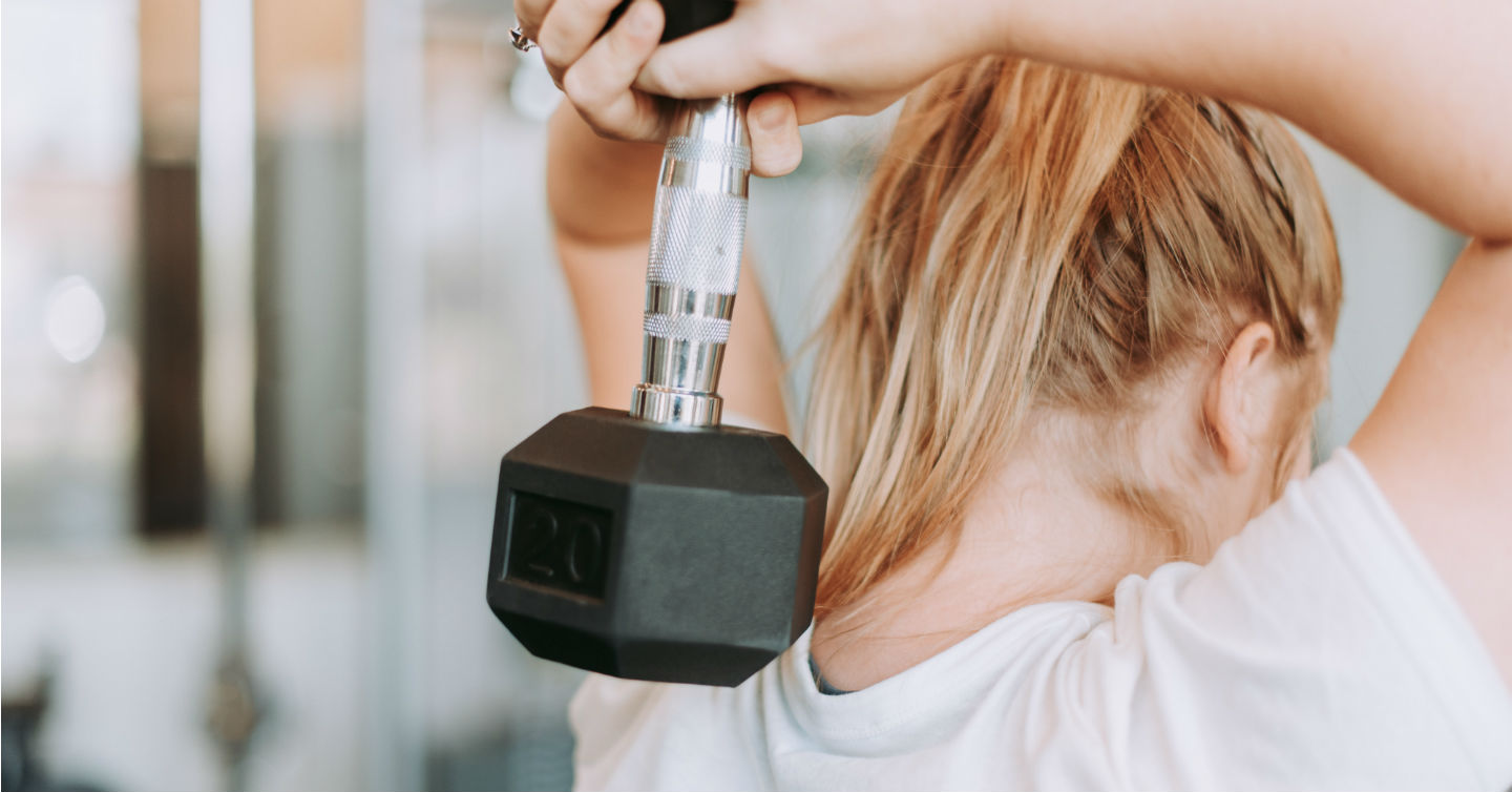 woman lifting weight behind her head