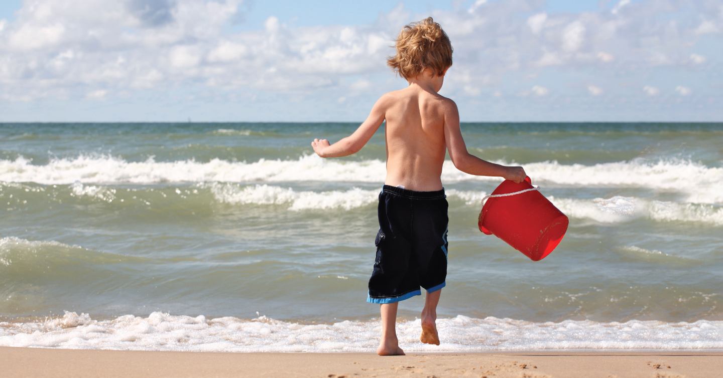 kid playing with a bucket on the beach