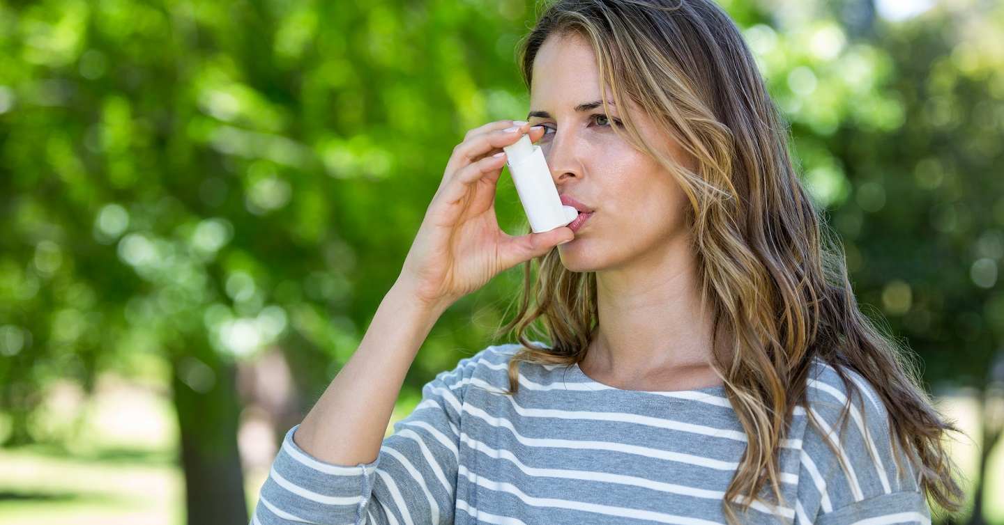 Person using asthma inhaler in park
